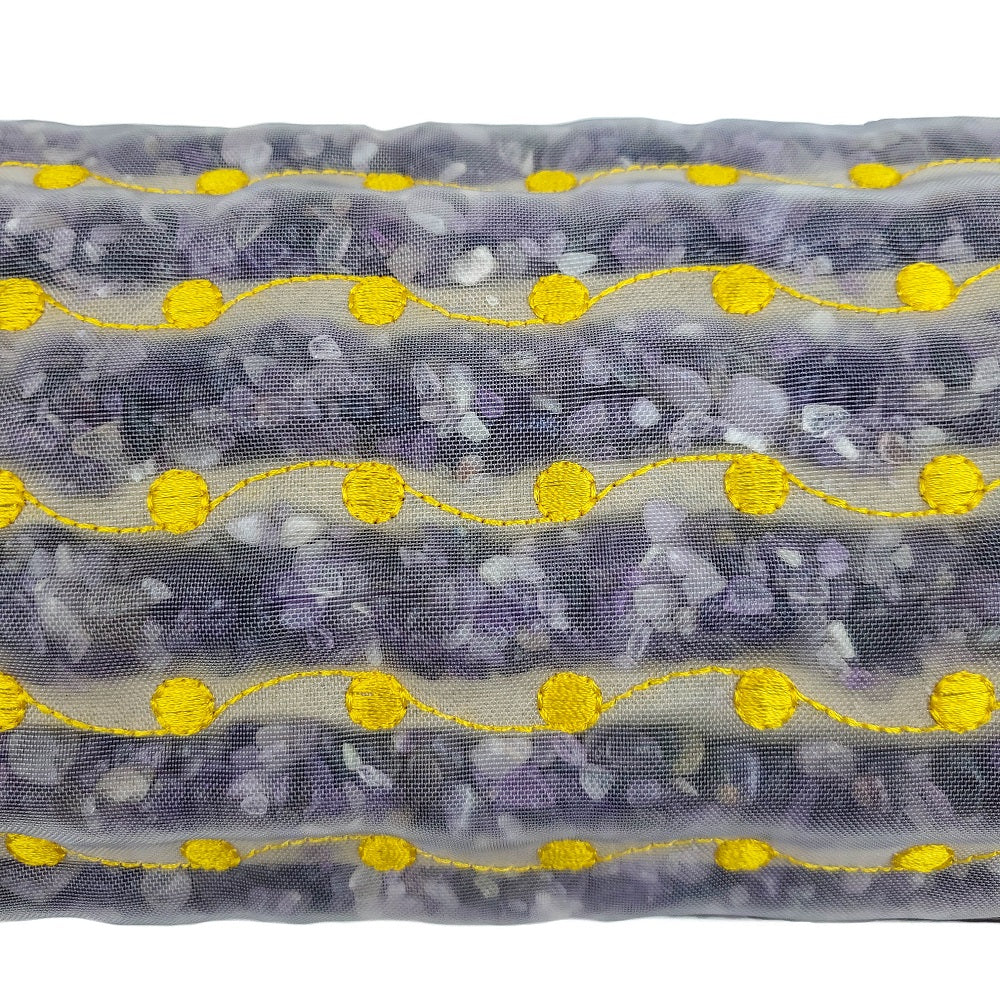 Close-up of a transparent pouch with small purple and white items and yellow stitching, inspired by HealthyLine's Amethyst Bolster Firm - Heated InfraMat Pro®, which may offer subtle natural healing benefits.