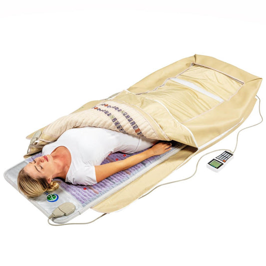 A woman relaxes inside the HealthyLine Platinum 360 Wrap Set Full 7224 - Photon Advanced PEMF, a beige infrared sauna blanket that covers her body (except head and feet) as she enjoys a full-body experience with its nearby control panel.