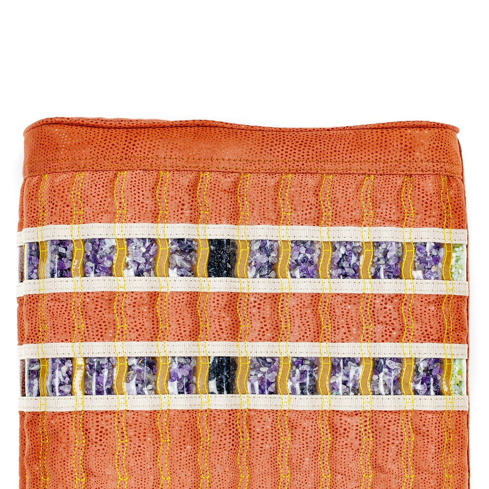 Close-up of the TAO-Mat® Pillow Soft InfraMat Pro® by HealthyLine, featuring a folded textile with an orange textured surface and decorative amethyst-toned stripes, showcasing sections with purple, black, and white patterns bordered by yellow stitching.