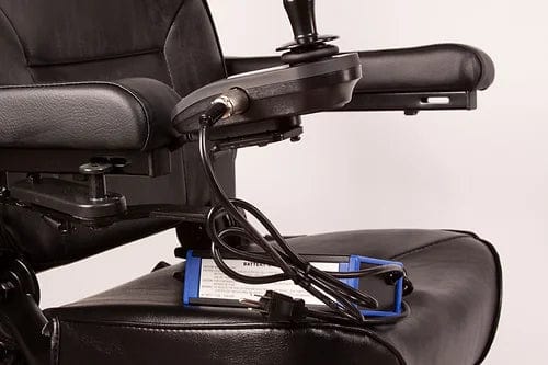 Close-up of the E-Wheels EW-M31 Compact Power Chair's joystick control and armrest, with a power cord and clipboard resting on the seat.