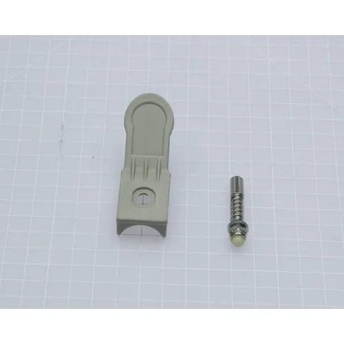 A gray plastic bracket and a small metal pin with a spring are arranged on a white grid-patterned background, resembling parts from the Direct Supply® Bariatric Drop Arm Commode's Release Mechanism.