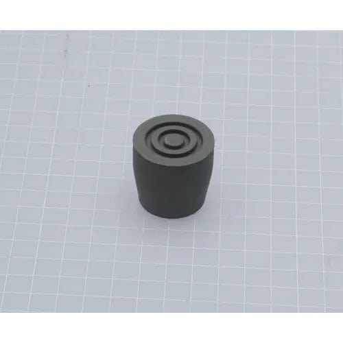 A small, cylindrical object with a flat top and concentric circles rests on a gray grid background, reflecting the careful design of Direct Supply's Rubber Feet for Transfer Bench.