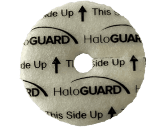 The HALOGuard™ Protective Disc by ATTWILL Medical is a round foam pad with a central hole labeled "HaloGUARD This Side Up," featuring arrows for proper orientation. It uses chlorhexidine gluconate for antimicrobial protection to help reduce bloodstream infections.