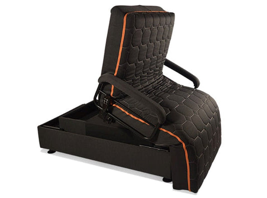 The Upbed Standard by Journey Health & Life Style is a dark upholstered chair with orange piping that easily transforms into a bed. It features a partially reclined back revealing a cushioned, quilted surface and includes a storage compartment underneath.