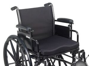 The Drive Medical Molded Foam Wheelchair Cushion is a black manual wheelchair with large rear wheels, small front wheels, armrests, and footrests. It features a sturdy metal frame, vapor permeable fabric for comfort, and pressure redistribution technology for optimum support.