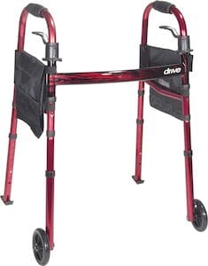 Introducing the Travel Walker with Folding Legs by Drive Medical—a red walker that combines convenience and functionality. This mobility aid features folding legs for easy storage, two front wheels, rubber tips at the back for stability, side pouches for extra storage, and black hand grips designed to assist with mobility.