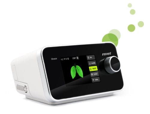 The Resvent iBreeze BiPAP Machine, in white, comes with a digital screen displaying a green leaf design, making it ideal for managing sleep apnea. This device features various buttons and settings and is adorned with green bubbles in the upper right corner.