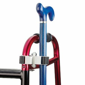 A Medline metallic walker, highlighted as essential mobility assistance equipment, comes in red with a blue cane attached using a black and white clamp. It also features an ergonomic handle and a Cane Holder.