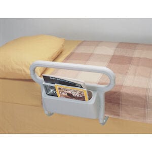 The Maddak Inc Bed Rail AbleRise 1EA attaches to the side of a bed with a brown and beige checkered blanket. It has a built-in pocket for easy access to reading materials like magazines and booklets for added convenience.