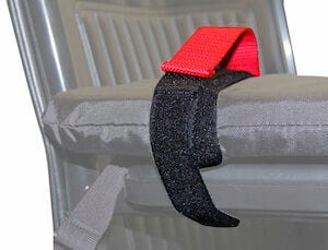 A Soft Top Wheelchair Lap Tray by Skil-Care, in gray color, is placed on a metal folding chair. It is secured with a black strap and features a vinyl cover, with a red handle attached to the strap.