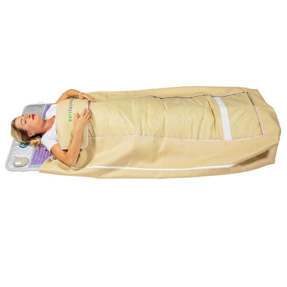 A person lies on a 360 Wrap Set™ Platinum & SOFT Full Pro PLUS 7428 - Photon Advanced PEMF InfraMat Pro® by HealthyLine, wrapped in a beige thermal blanket. With advanced gemstone technology controls at their side, they appear relaxed and soothed, enjoying the full-body experience.