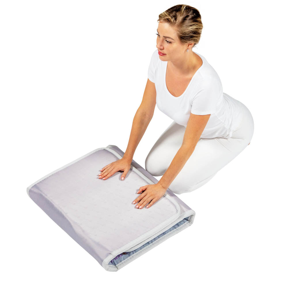 A woman in white kneels on the floor with both hands on a HealthyLine Platinum Mat Full Short 6024, featuring 30 Photon LED and advanced PEMF, against a plain white background.