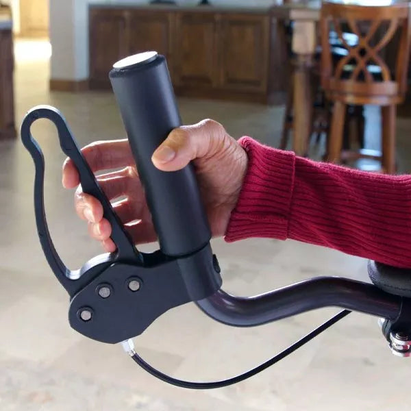 A person’s hand grips a bicycle handlebar with a custom lever attachment for mobility support, similar to the assistance provided by the Journey Health & Life Style UpWalker H200 Standard Large device.