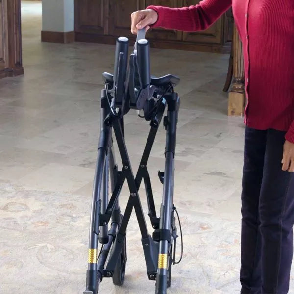 A person in a red sweater folds a Journey Health & Life Style UpWalker H200 Standard Large rollator with multi-terrain wheels on a light floor at home—ideal for those with mobility challenges.