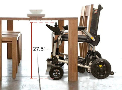 The Zoomer by Journey Health & Lifestyle, featuring a detachable battery and one-handed joystick steering, fits under wooden dining tables 27.5 inches high, showcasing its compatibility with standard table heights.