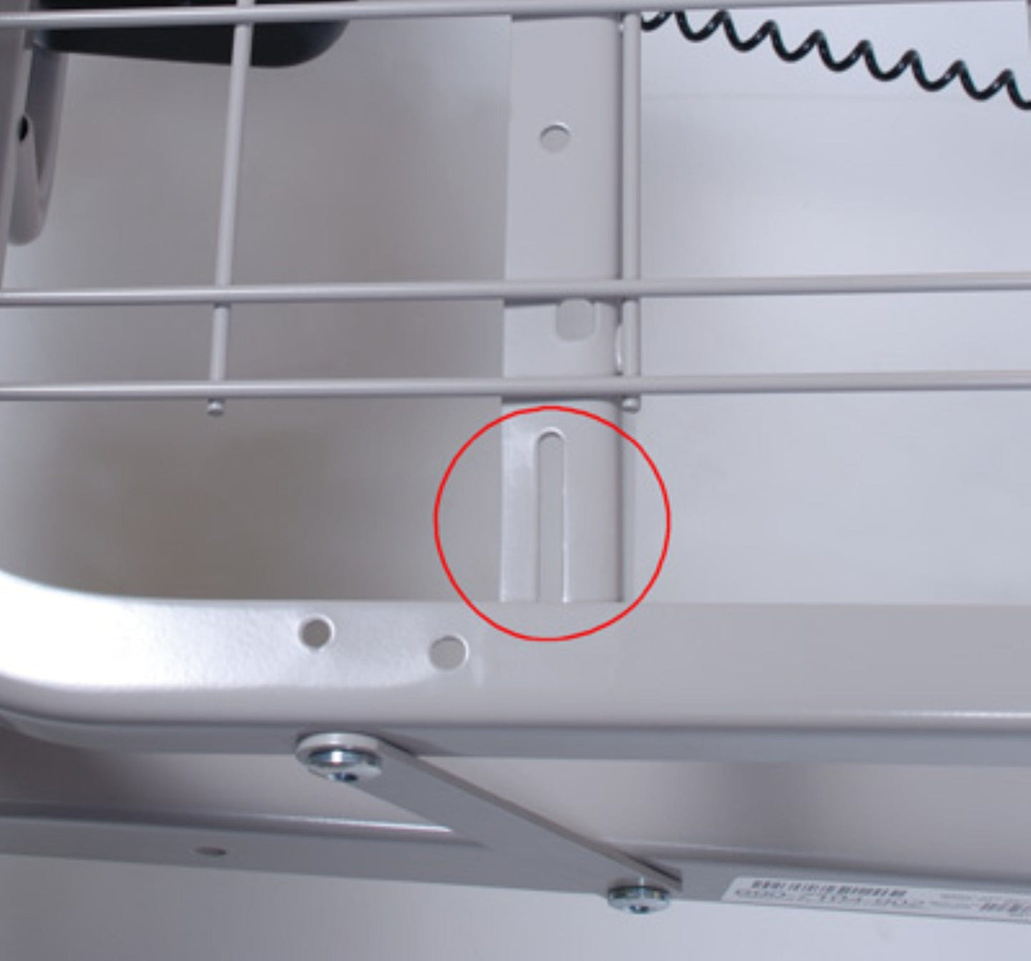 A close-up of a metal frame with a red circle highlighting a vertical notch in the support structure, reminiscent of the grid sleep surface seen in Graham Field's Patriot Homecare Beds, Semi-Electric. The frame’s wire grid elements are integral to this mechanical assembly, proudly MADE IN THE USA.